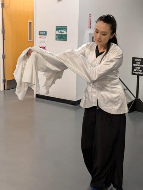 A young woman performs a traditional Chinese dance using long, silk sleeves
