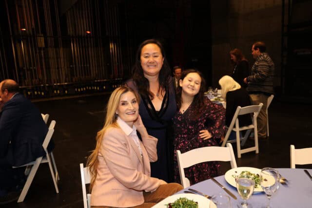 Two women and a child pose for the camera at a luncheon