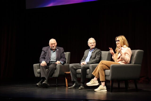 Three people in chairs on stage