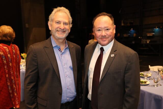 Two men smile for the camera at a luncheon