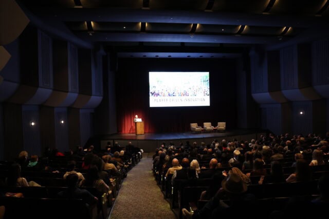 Wide view of a theatre audience watching a lecture