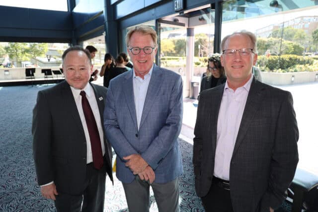 Three people smile for the camera in a theatre lobby