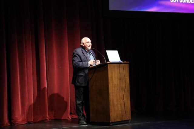 A man speaking from a lectern on stage