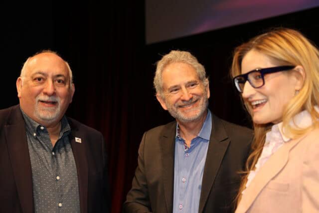 Three people smile for the camera